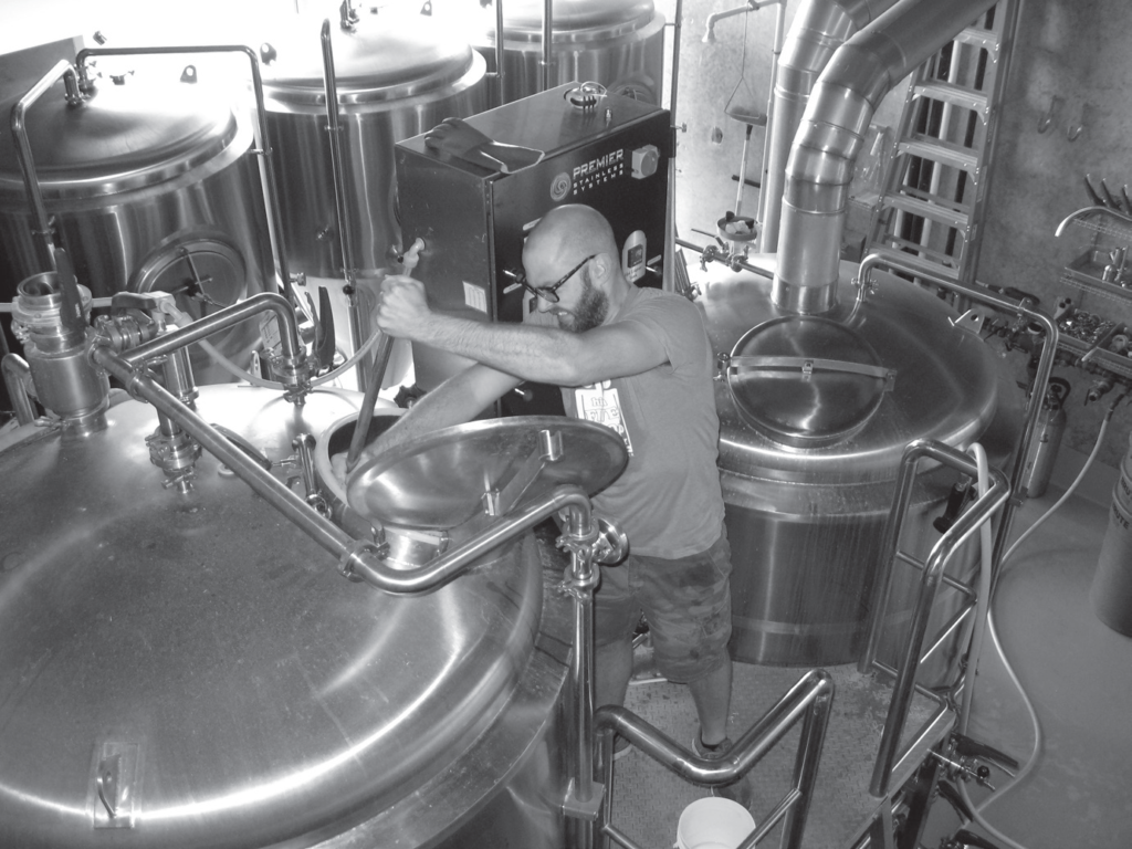A man stirs a brewery cauldron.