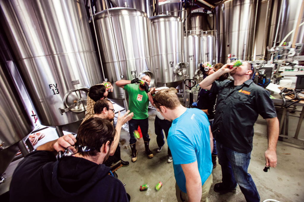 A photo of a group of brewery workers shotgunning beers on Shotgun Friday.