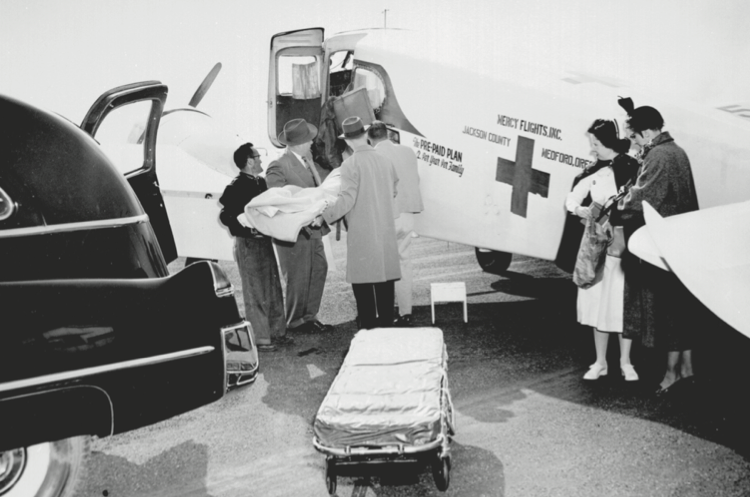 A photo of a patient being loaded into a mercy flight plane by doctors and nurses
