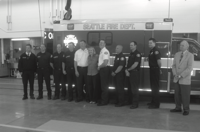 Paramedics and firefighters posing in front of an ambulance