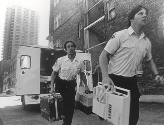 Two paramedics from the 1970s running out of the back of an ambulance