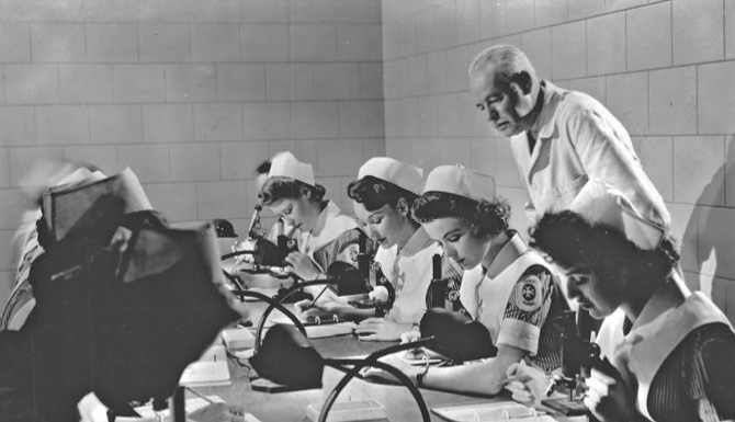 A still from a short film about cadet nurses showing young women taking a practice exam