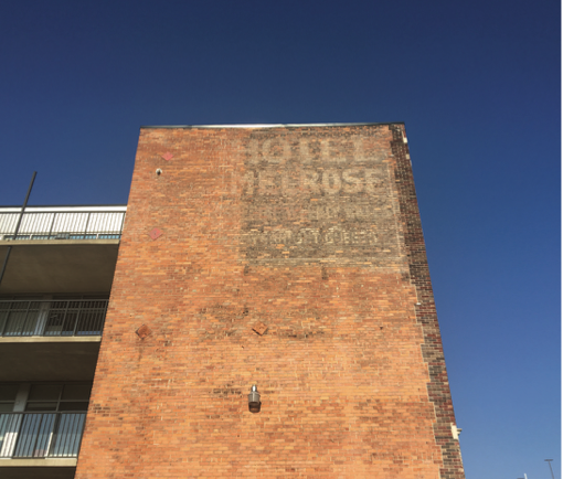 A faded advertisement for the Melrose Hotel on a brick building 