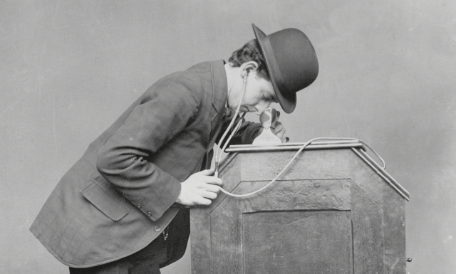A man looking into a kinetoscope