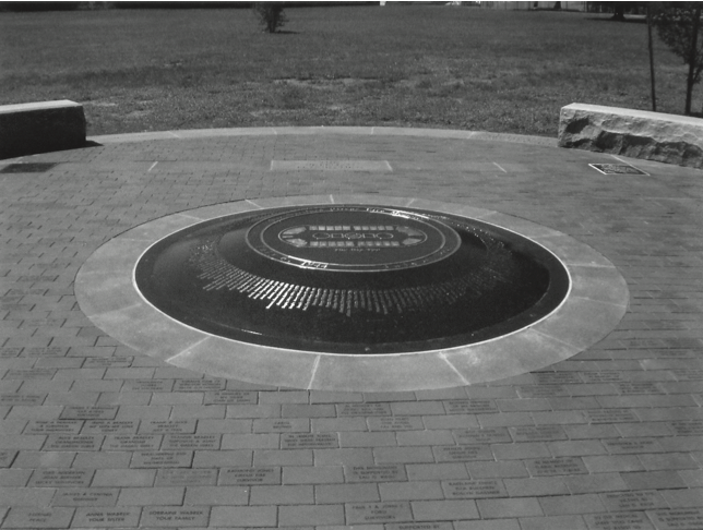 A photo of a circular memorial on the ground with the names of the victims engraved around it.
