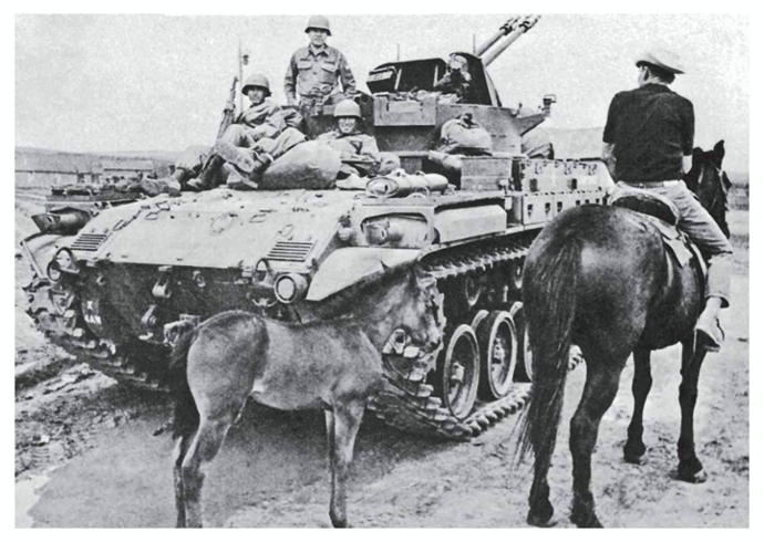 Members of the New Mexico National Guard on a tank and on a horse. A donkey stands behind the horse.