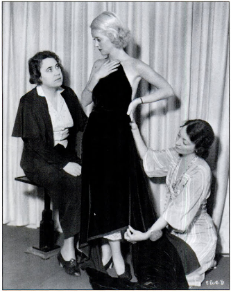 Two women fitting actress Bette Davis for a film costume.